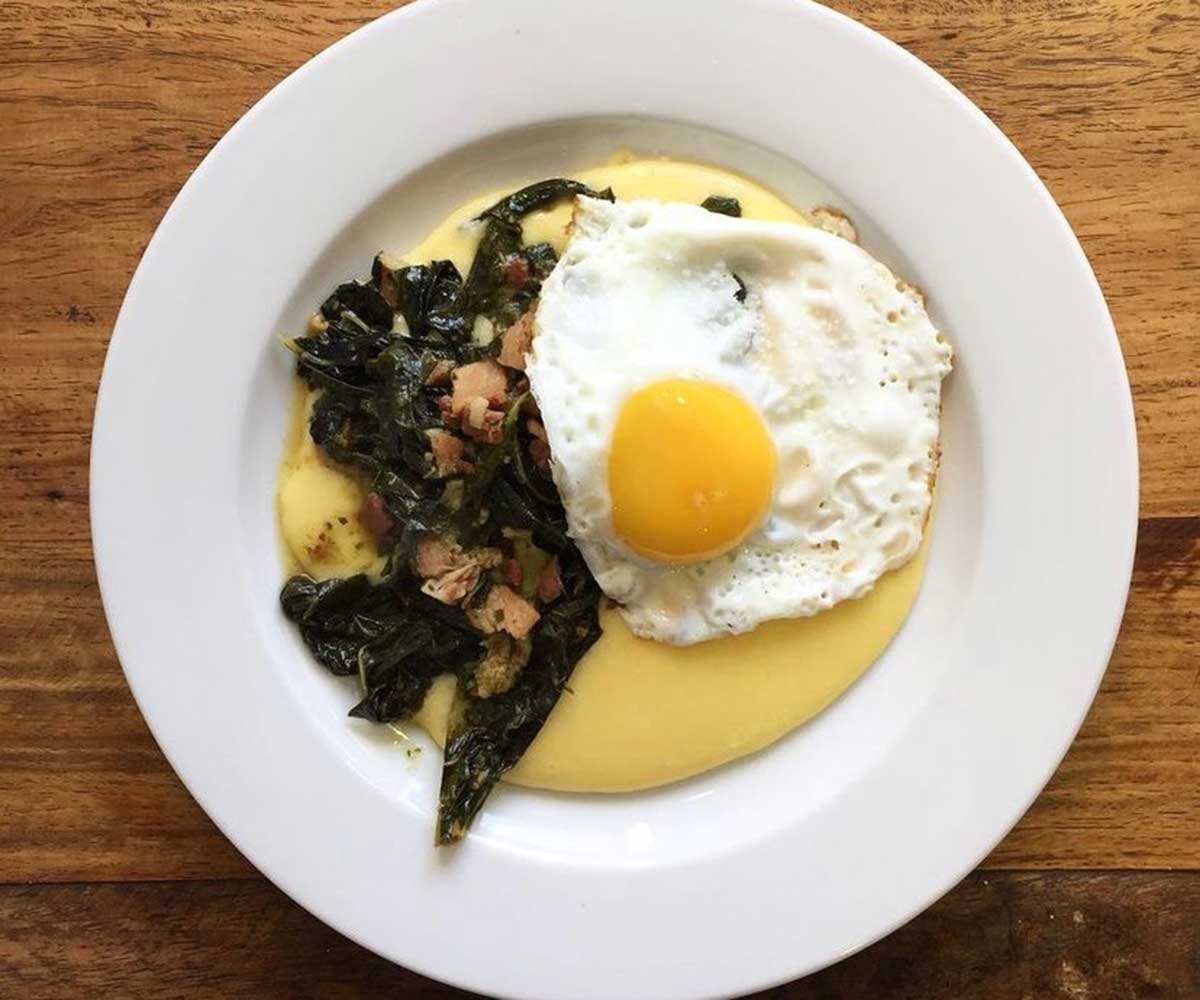 Cromwell Greens on a white plate with a friend egg and on a bed of polenta