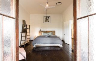 Cromwell Farmhouse bedroom with white walls, queen sized bed, grey linen bedding, white ceiling fan