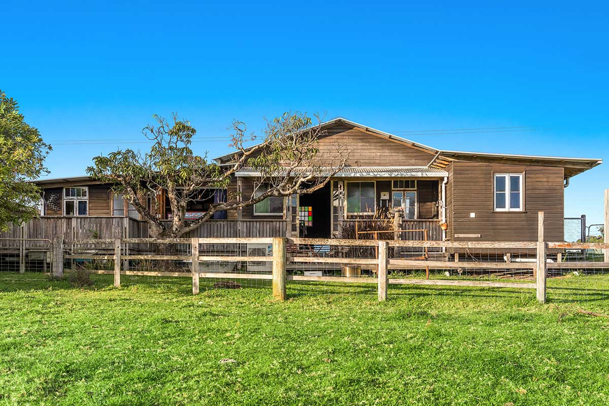 A wooden house with a fence and grass field called Middle Shed