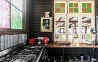 A dark coloured kitchen with multi coloured window panes