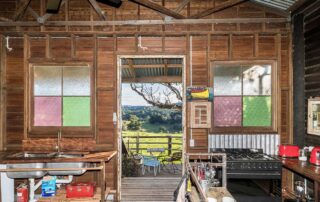 Middle Shed dark wooden kitchen with a door open to show the green farmland outside