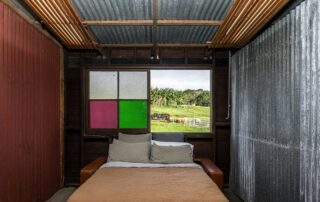 Middle Shed lounge room with a pull out sofa bed and coloured glass window that is open to a green field
