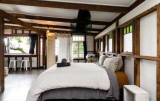 Middle Shed main bedroom with a queen bed with white linen sheets and a window that looks out to a tree