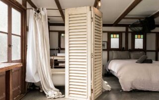 Middle Shed main bedroom with interior bath and cream bath curtain and a cream privacy tri-fold screen and a queen bed
