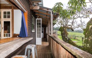 Middle Shed back deck with stools at a breakfast bar and coloured window coverings