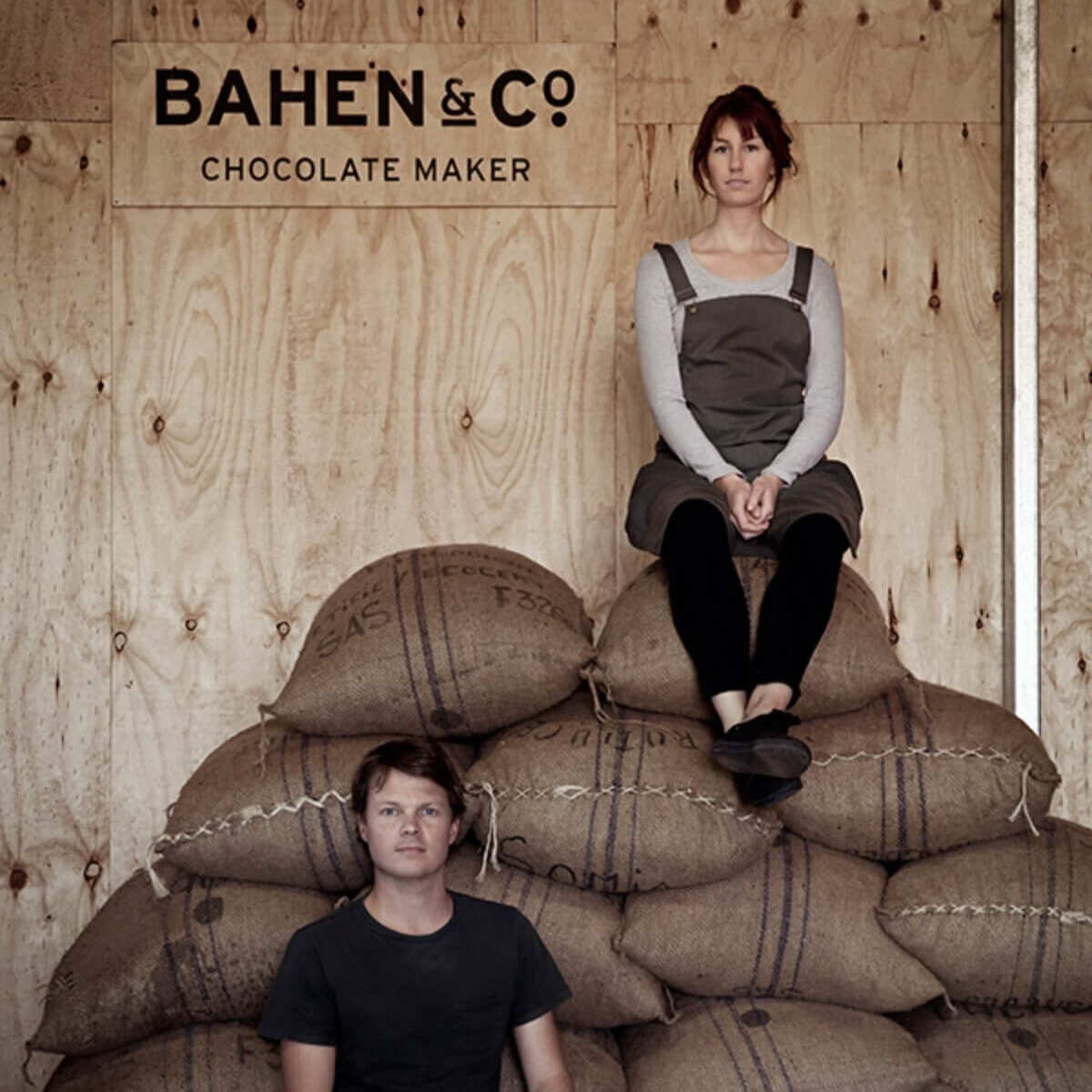 A man and a woman sit on hessian cacao sacks