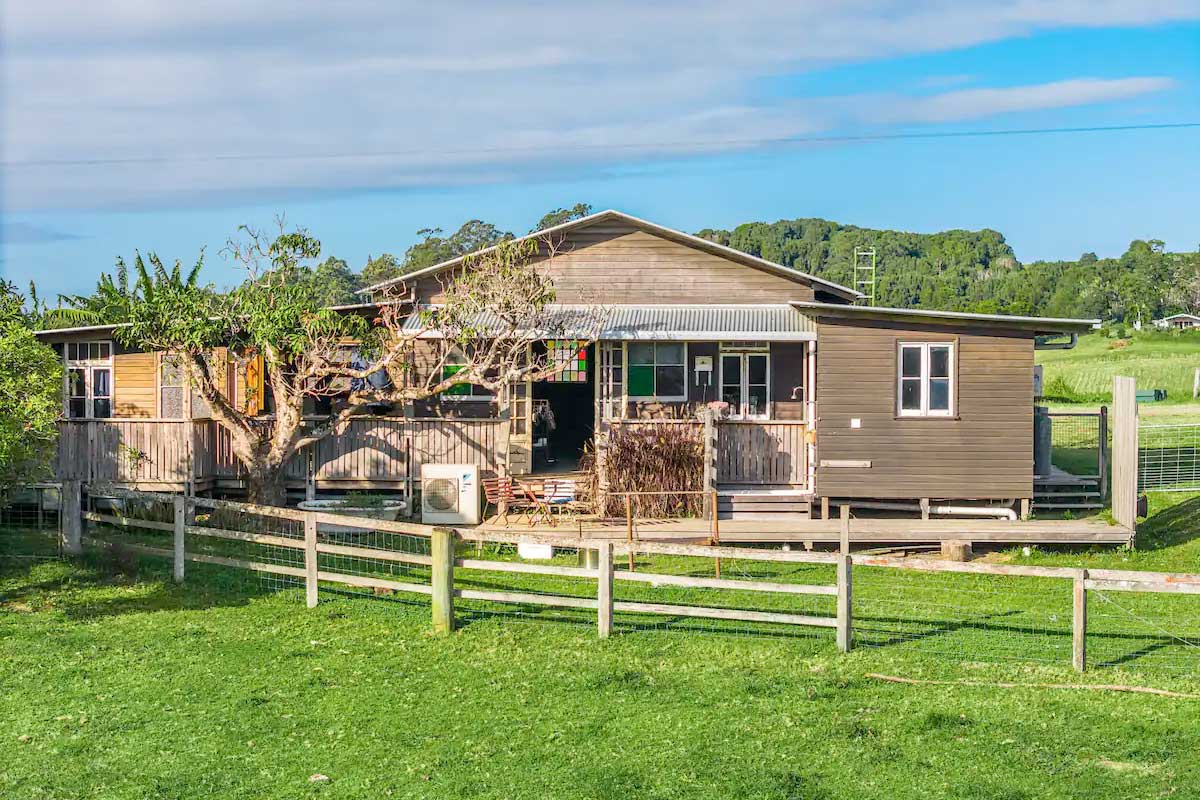 A wooden house with a fence and grass field called Middle Shed